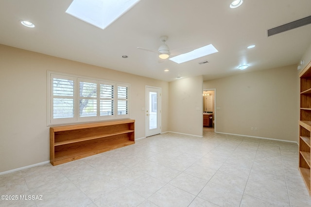 unfurnished room featuring a skylight and ceiling fan