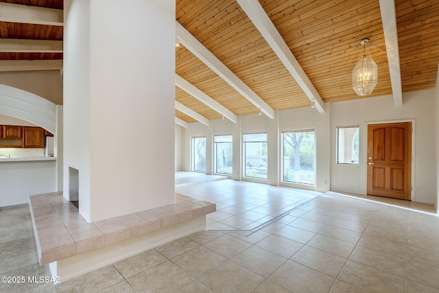 tiled spare room featuring beamed ceiling, a chandelier, high vaulted ceiling, and wooden ceiling