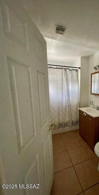 bathroom featuring tile patterned flooring, a shower with curtain, vanity, and toilet