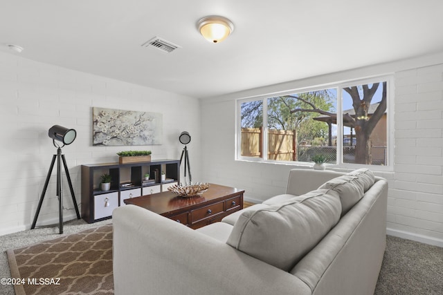 carpeted living room featuring brick wall