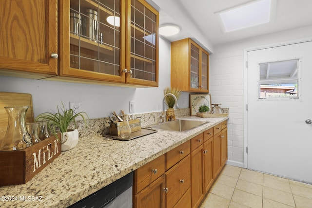 kitchen featuring light tile patterned floors, light stone counters, and sink