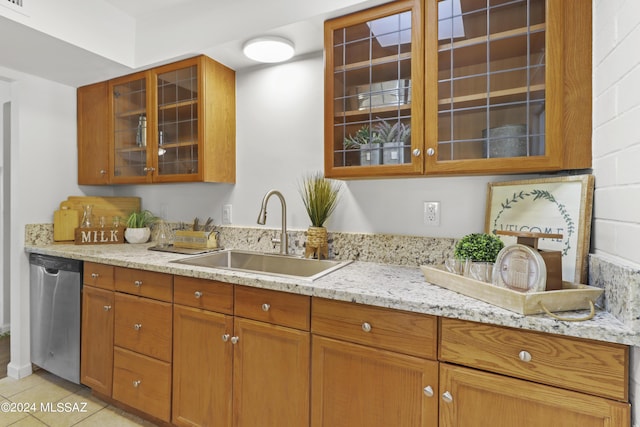 kitchen featuring light tile patterned floors, light stone counters, stainless steel dishwasher, and sink