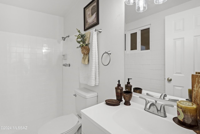 bathroom with a tile shower, vanity, and toilet