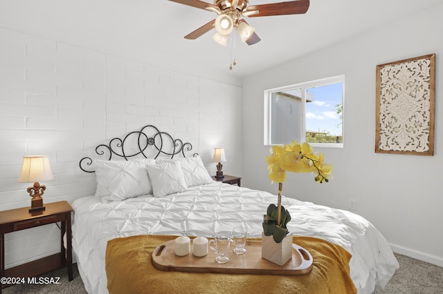 carpeted bedroom with ceiling fan and brick wall