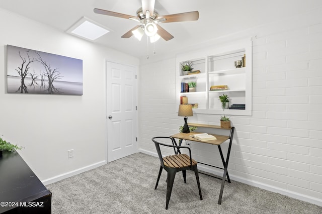 home office with light carpet, ceiling fan, and brick wall