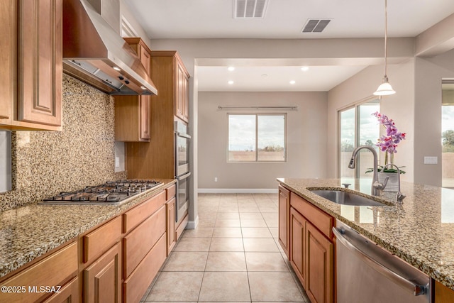 kitchen featuring visible vents, decorative backsplash, wall chimney range hood, a sink, and appliances with stainless steel finishes