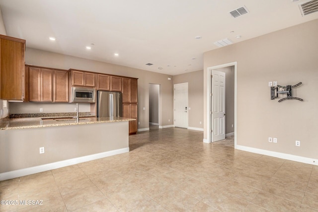 kitchen with stainless steel appliances, visible vents, brown cabinetry, and a peninsula