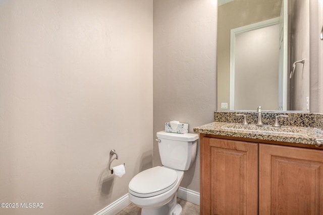 bathroom featuring baseboards, vanity, and toilet