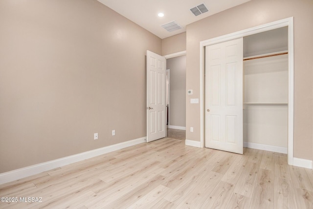 unfurnished bedroom with baseboards, a closet, wood finished floors, and visible vents