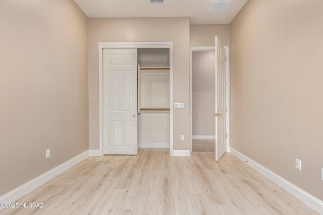 unfurnished bedroom featuring visible vents, baseboards, wood finished floors, and a closet