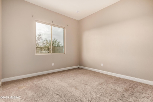 carpeted empty room featuring baseboards