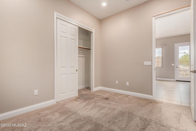 unfurnished bedroom with carpet floors, baseboards, a closet, and tile patterned flooring
