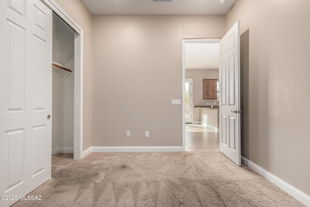 unfurnished bedroom with baseboards, light carpet, and a closet