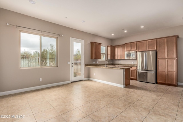 kitchen with a peninsula, recessed lighting, a sink, appliances with stainless steel finishes, and light tile patterned floors