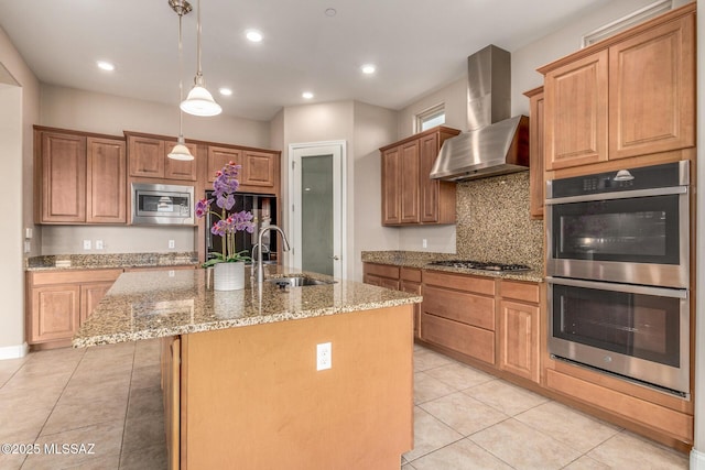 kitchen with wall chimney range hood, appliances with stainless steel finishes, a sink, light tile patterned floors, and light stone counters