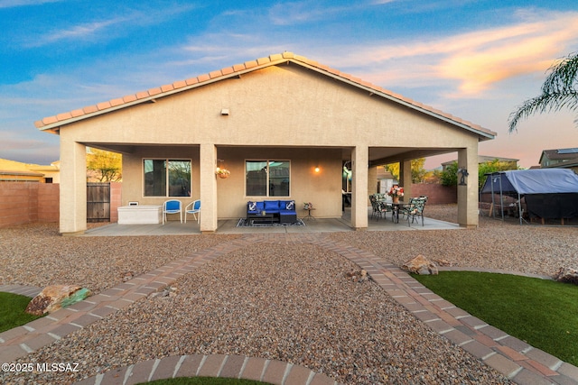 back house at dusk with a patio area