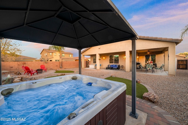 pool at dusk with a patio area and a hot tub