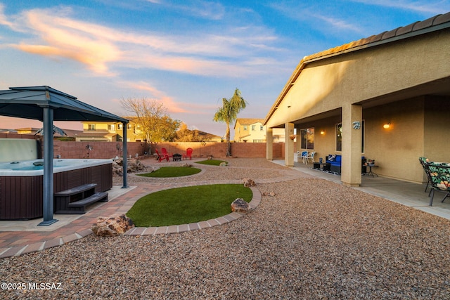 yard at dusk featuring cooling unit, a patio, and a hot tub