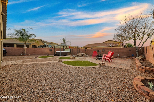 yard at dusk with a gazebo, a patio, and a fire pit