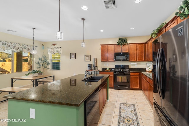 kitchen with decorative light fixtures, sink, an island with sink, and black appliances