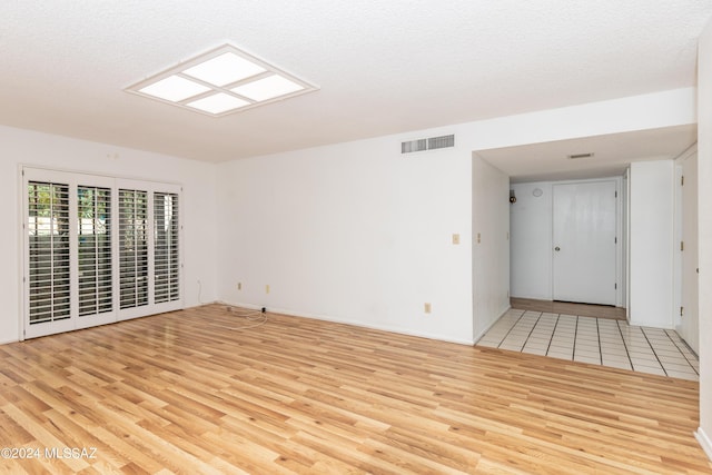 spare room featuring a textured ceiling and light hardwood / wood-style flooring