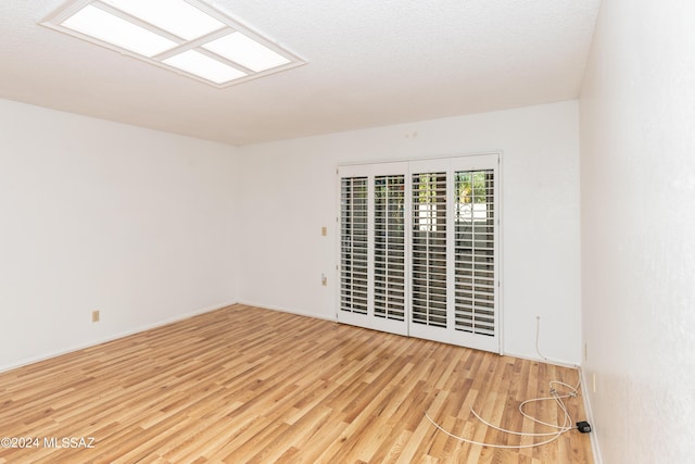 unfurnished room with light wood-type flooring and a textured ceiling