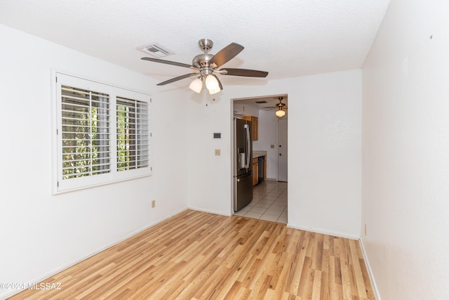 empty room featuring ceiling fan, a textured ceiling, and light wood-type flooring