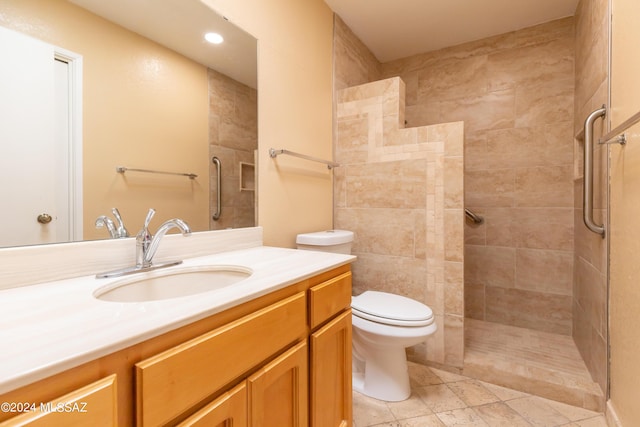 bathroom featuring vanity, toilet, and a tile shower