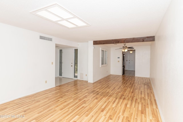 unfurnished room with beam ceiling, ceiling fan, and light hardwood / wood-style floors