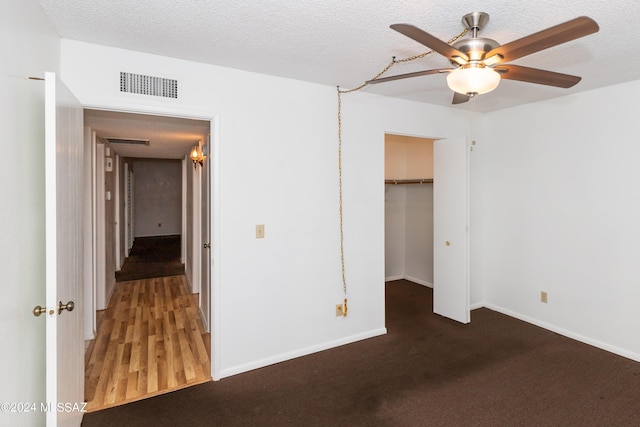 unfurnished bedroom featuring ceiling fan, a spacious closet, a textured ceiling, and a closet