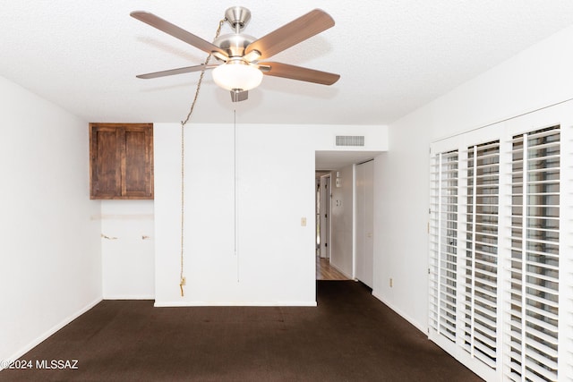 interior space with ceiling fan, dark carpet, and a textured ceiling