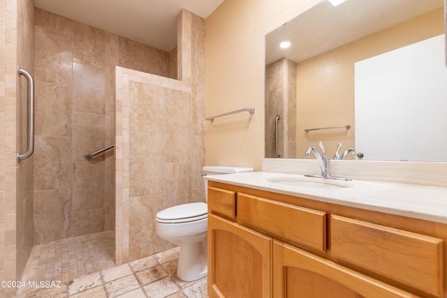 bathroom with tiled shower, vanity, and toilet