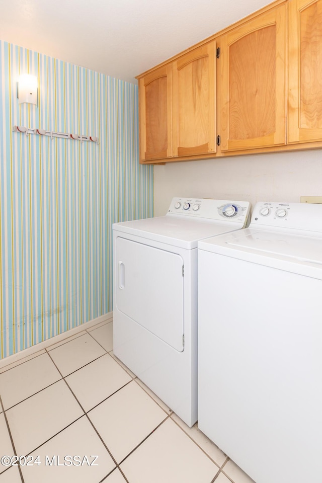 laundry room featuring cabinets, light tile patterned floors, and washing machine and dryer