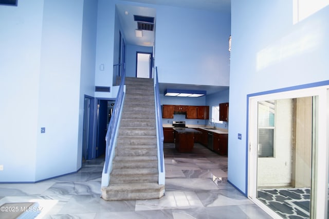 stairs with a wealth of natural light, sink, and a towering ceiling