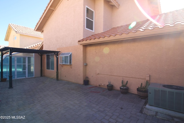 rear view of property featuring central air condition unit, a patio, a tiled roof, and stucco siding