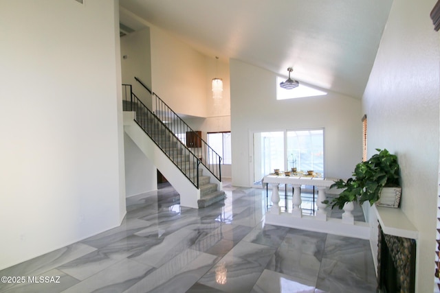 foyer with marble finish floor, a high ceiling, and stairs