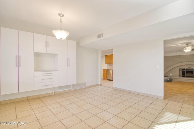 empty room with a fireplace, light tile patterned floors, and ceiling fan