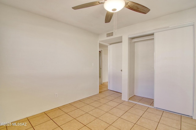 unfurnished bedroom with ceiling fan, light tile patterned flooring, and a closet