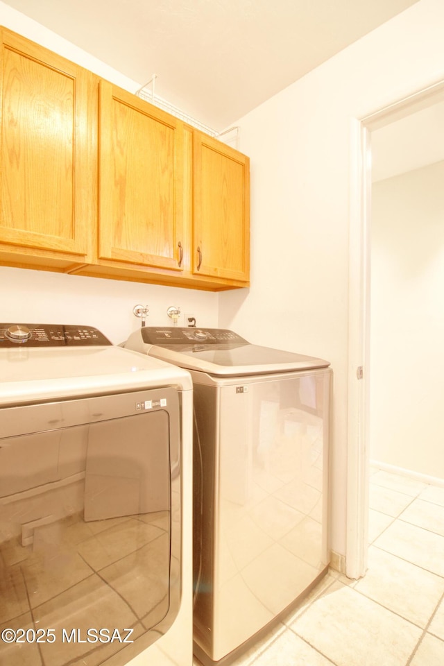 laundry area featuring cabinets, light tile patterned floors, and washing machine and dryer