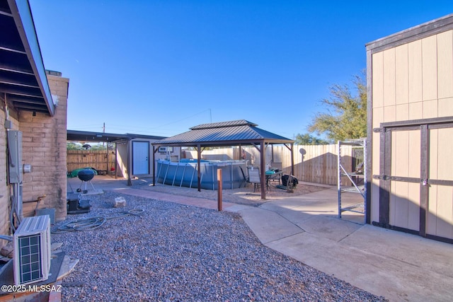 view of yard with a covered pool, ac unit, a storage shed, a gazebo, and a patio area