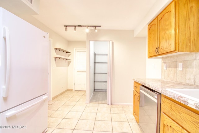 kitchen featuring dishwasher, tasteful backsplash, white refrigerator, track lighting, and light tile patterned floors