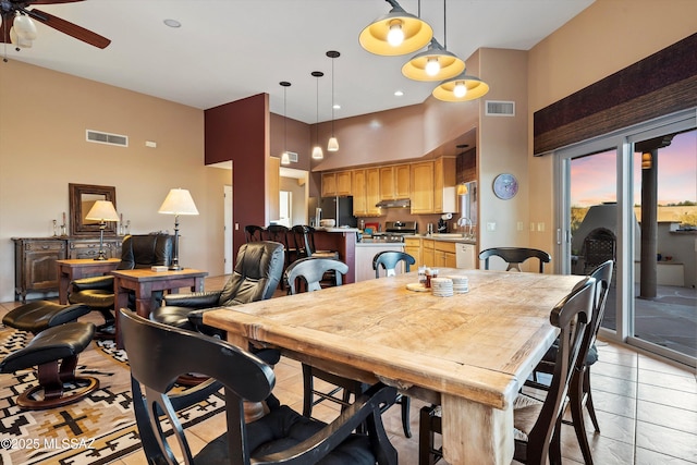 dining room featuring sink, ceiling fan, a towering ceiling, and light tile patterned floors