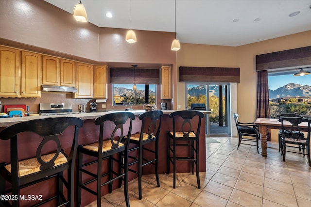 kitchen with a healthy amount of sunlight, decorative light fixtures, a mountain view, and light tile patterned floors