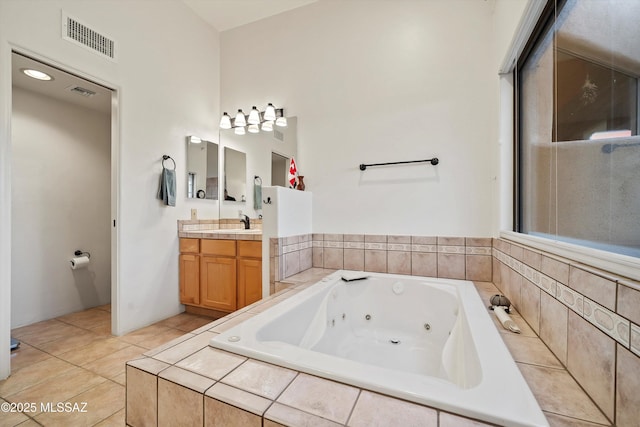 bathroom featuring vanity, tile patterned flooring, and a relaxing tiled tub