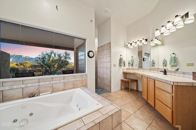 bathroom featuring tile patterned flooring, tiled tub, and vanity