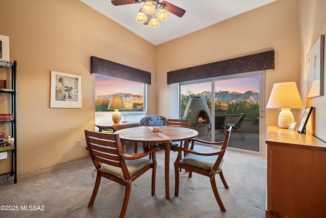 carpeted dining room with vaulted ceiling and ceiling fan