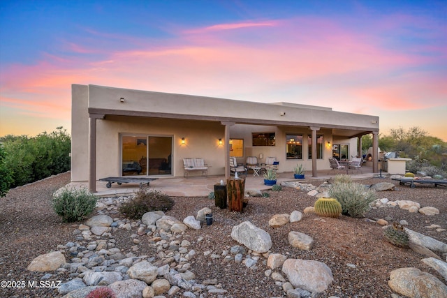 back house at dusk featuring a patio area