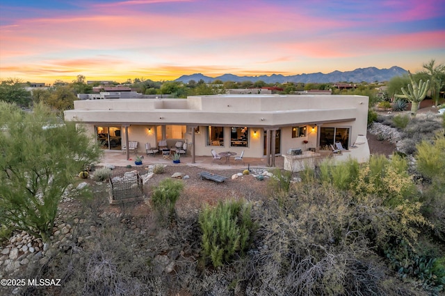 back house at dusk featuring a patio and a mountain view