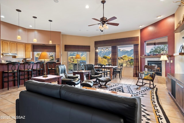 living room with a tile fireplace, ceiling fan, light tile patterned floors, and a healthy amount of sunlight