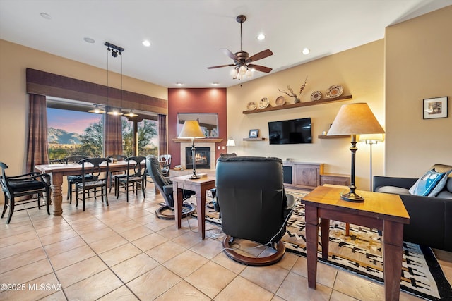 tiled living room featuring a fireplace and ceiling fan